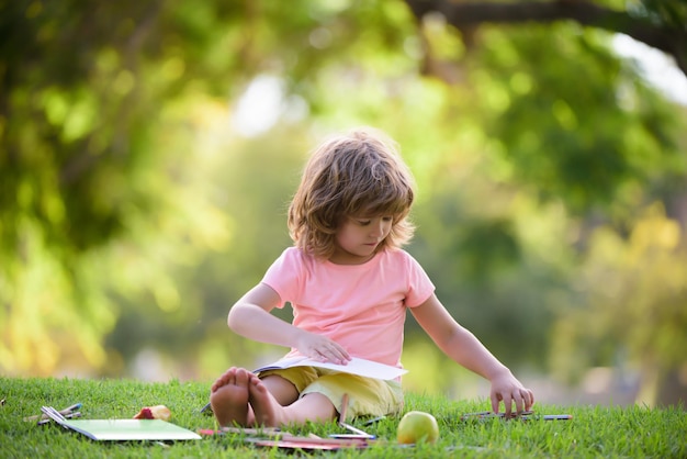 Scolaro che studia i compiti nell'educazione dei bambini all'aperto del parco