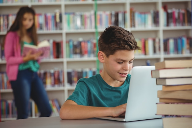 Scolaro che utilizza computer portatile nella biblioteca