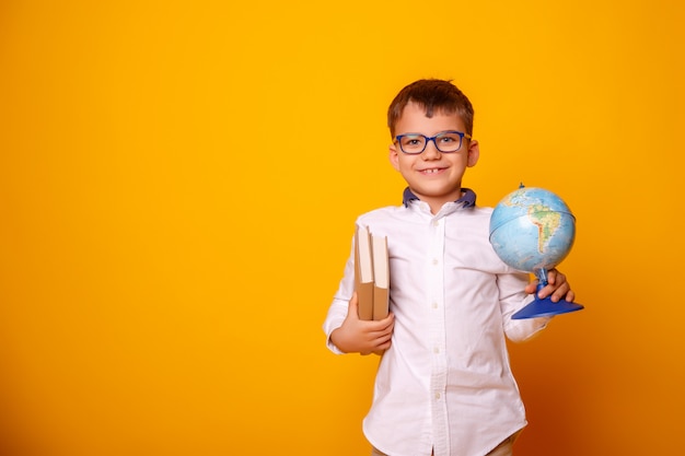 Scolaro con i vetri che tengono i libri e un globo della terra