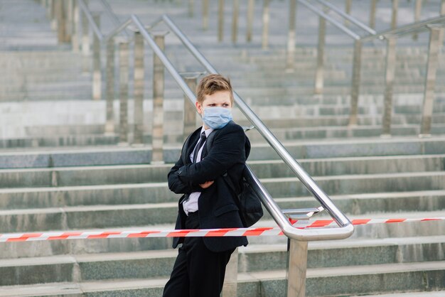 Scolaro esce da scuola indossando una maschera protettiva in città