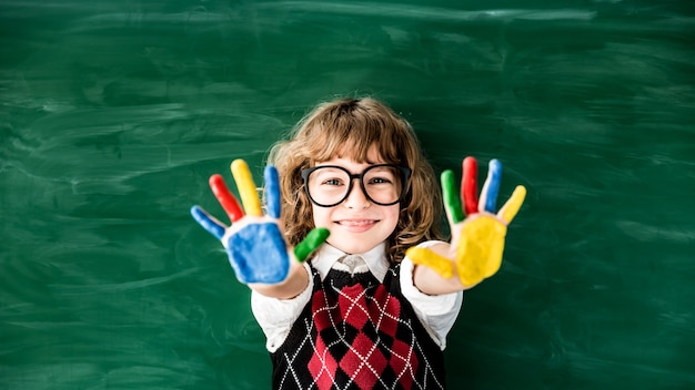 Scolaro in classe Bambino felice contro la lavagna verde Concetto educativo