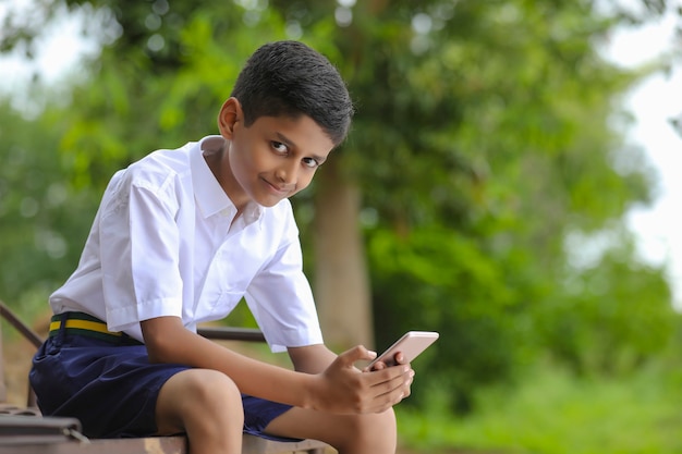 Scolaro indiano che utilizza lo schermo dello smartphone concetto di educazione online.