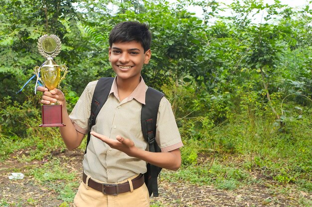 Scolaro intelligente che alza il suo trofeo come vincitore in una competizione scolastica