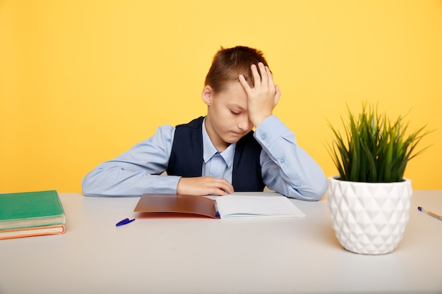 Scolaro malato e stanco seduto alla scrivania e studiando.