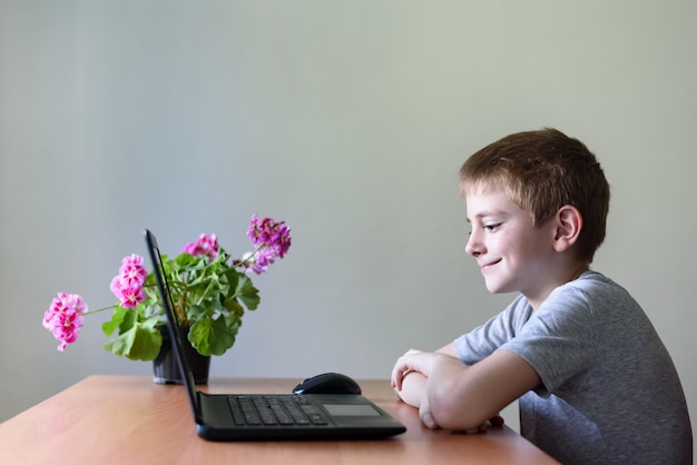 Scolaro sorridente che si siede ad un computer portatile