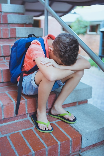 Scolaro triste che si siede da solo sulla scala