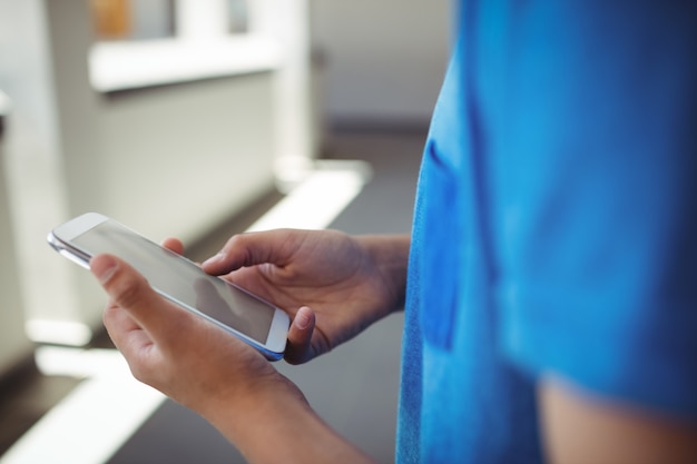 Scolaro utilizzando il telefono cellulare in corridoio a scuola