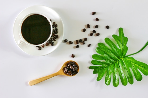 Scolpisci la foto con una tazza di caffè, un cucchiaio di legno e una foglia tropicale