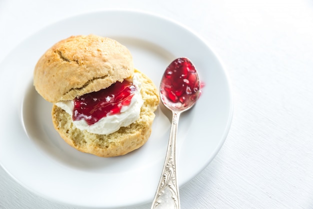 Scone con panna e marmellata di ciliegie sul piatto