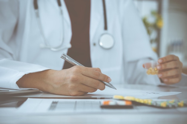 Sconosciuta donna-medico compila il modulo di prescrizione. avvicinamento. Panacea e salvavita, prescrivere cure, farmacia legale. Concetto di medicina.