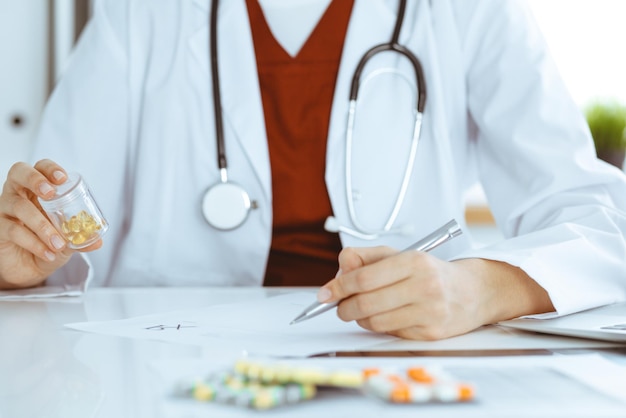 Sconosciuta donna-medico compila il modulo di prescrizione. avvicinamento. Panacea e salvavita, prescrivere cure, farmacia legale. Concetto di medicina.
