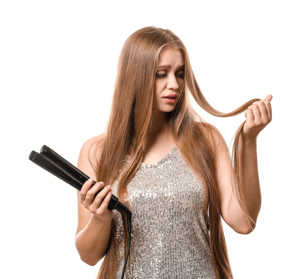 Sconvolto giovane donna con appiattimento ferro per capelli su sfondo bianco