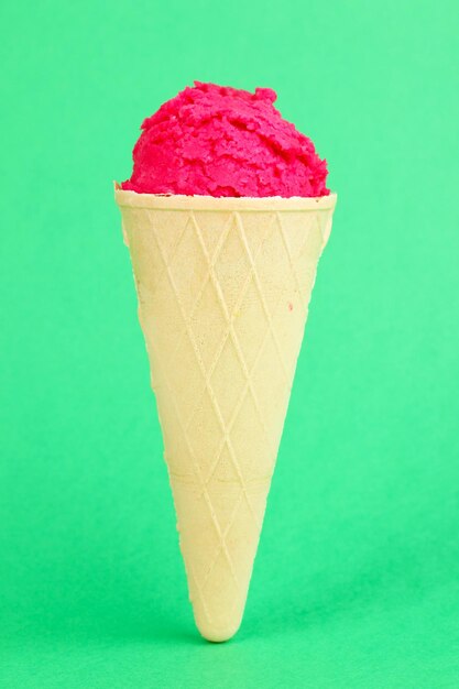 Scoop del gelato alla fragola nel cono di cialda su sfondo verde