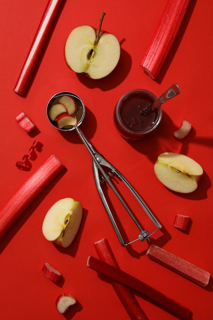 Scoop gambo barattolo di rabarbaro di marmellata e mela su sfondo rosso flatlay