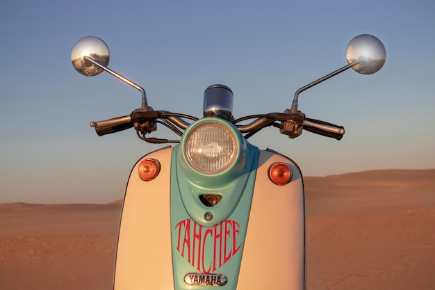 Scooter blu retrò al tramonto nella sabbia dorata del deserto del Namib