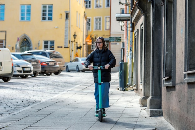 Scooter di guida dell'adolescente sul marciapiede