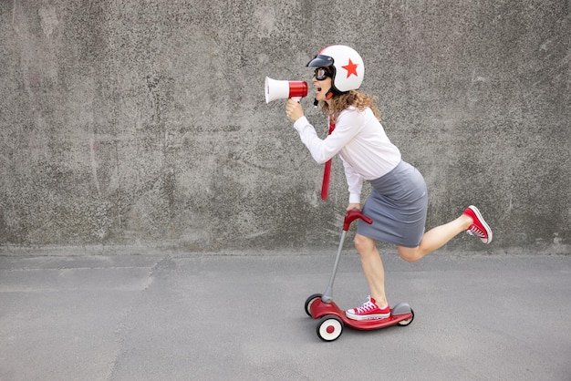 Scooter divertente di guida della donna di affari all'aperto