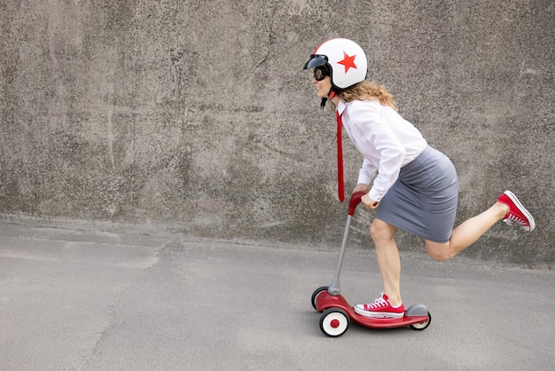 Scooter divertente di guida della donna di affari all'aperto