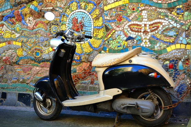 Scooter parcheggiato contro un muro di piastrelle multicolore