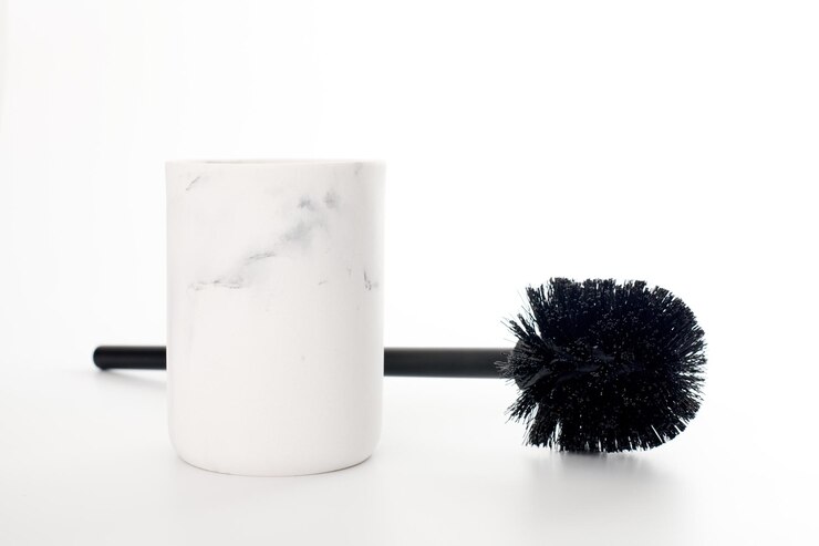 Scopino nero nel supporto di pietra bianco moderno isolato sfondo bianco. Strumento per WC per la pulizia del water. Spazzola per detergente per WC e candeggina per la superficie del water