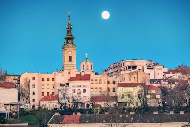Scopri la bellezza architettonica di Belgrado con le chiese e le torri che si affacciano sul panoramico fiume Danubio di notte con la luna piena