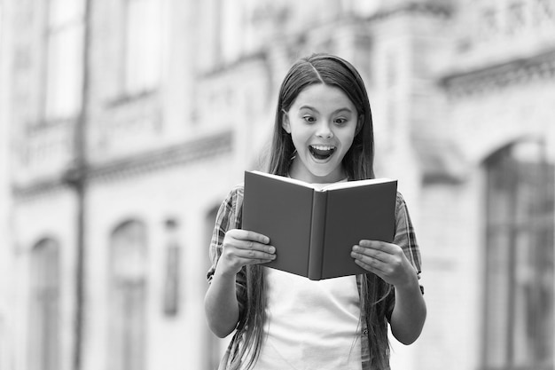 Scopri qualcosa di nuovo Bambino felice che legge un libro all'aperto Topo di biblioteca eccitato con la bocca aperta Biblioteca scolastica Letteratura di lettura Educazione all'alfabetizzazione Libro per bambini Libreria Il suo libro in punto