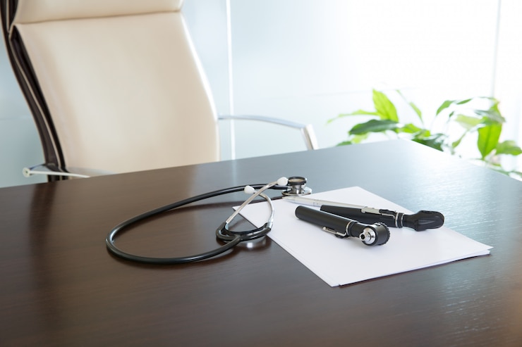 Foto scrittorio dell'ufficio del medico con lo stetoscopio e l'otoscopio