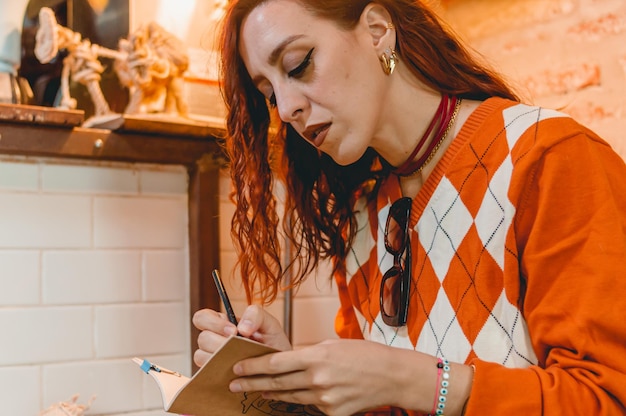 scrittrice della giovane donna del primo piano nel ristorante che si siede annotando le idee nel suo taccuino