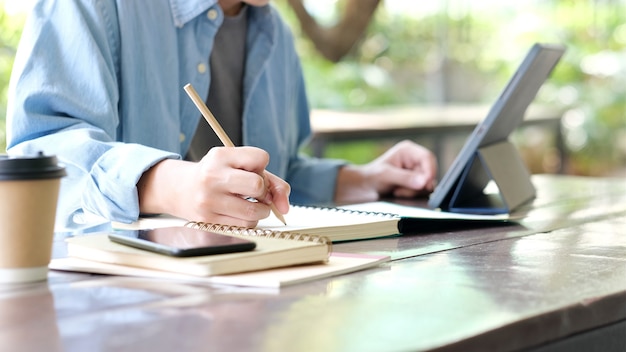 Scrittura a mano dell'uomo dello studente sul taccuino durante l'apprendimento online