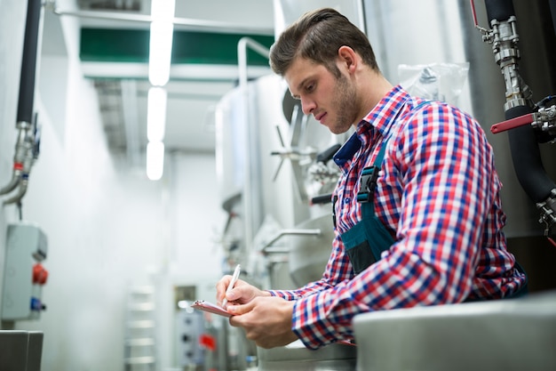 Scrittura del lavoratore di manutenzione sulla lavagna per appunti