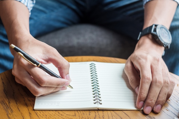 Scrittura dell&#39;uomo d&#39;affari qualcosa sul taccuino in ufficio