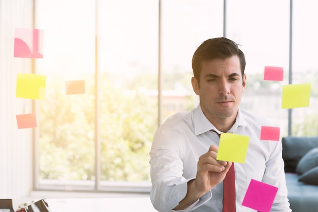 Scrittura dell'uomo d'affari sul Post-it a bordo.