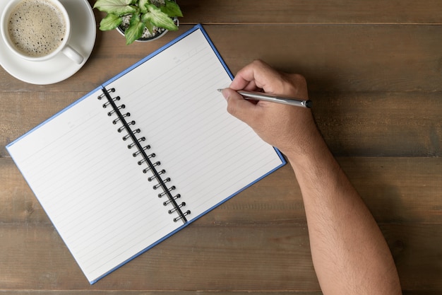 Scrittura dell'uomo d'affari sul taccuino in bianco