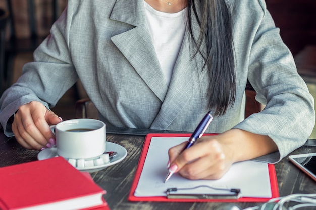 Scrittura della donna di affari in caffè.