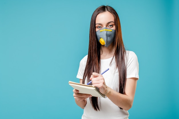 Scrittura della donna in maschera da portare del respiratore del taccuino