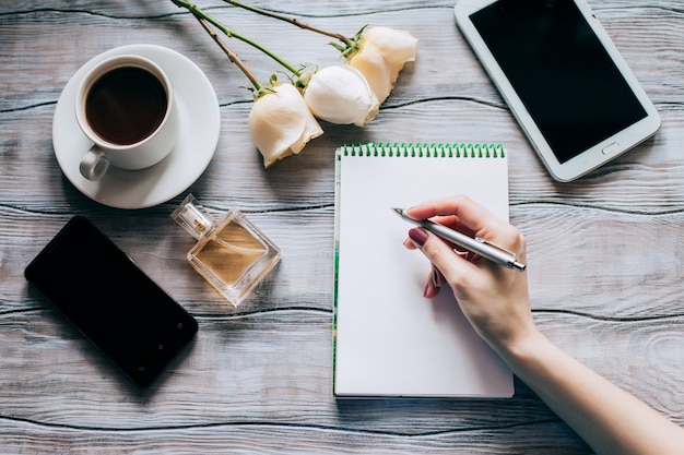 Scrittura femminile della mano sul taccuino Vista superiore sul posto di lavoro della donna.