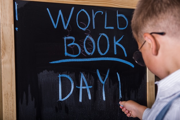 Scrittura sveglia del ragazzino nell'aula. Felice giornata mondiale del libro.