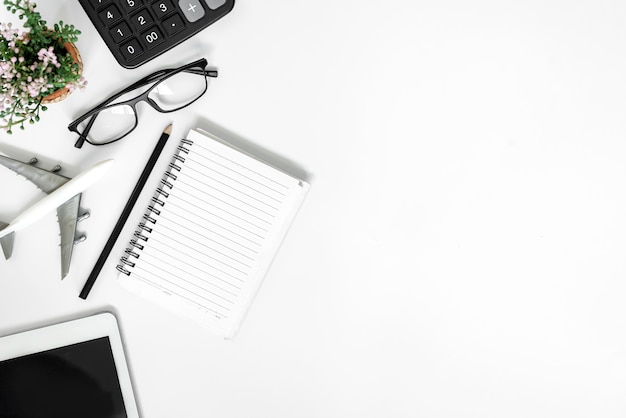 Scrivania da ufficio bianca. tavolo con taccuino vuoto, tablet, occhiali, calcolatrice, computer e altre forniture per ufficio. Vista dall'alto con copia spazio.