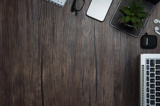 scrivania da ufficio in legno con auricolari cordless notebook bianco portatile e occhiali sfondo scuro