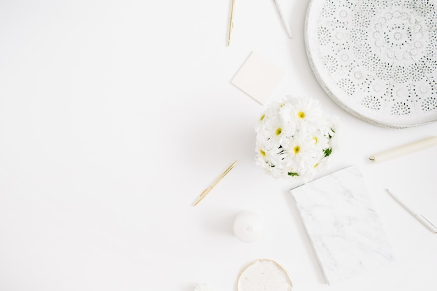 Scrivania da ufficio piatta. Area di lavoro della donna con bouquet di fiori di camomilla su bianco