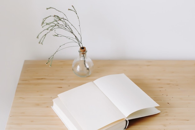 scrivania in legno con libro e fiori vista dall'alto