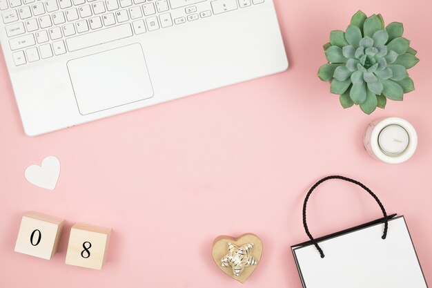 Scrivania piatta da ufficio. Area di lavoro femminile con laptop e dati sulla superficie rosa. 8 marzo giornata mondiale della donna concetto