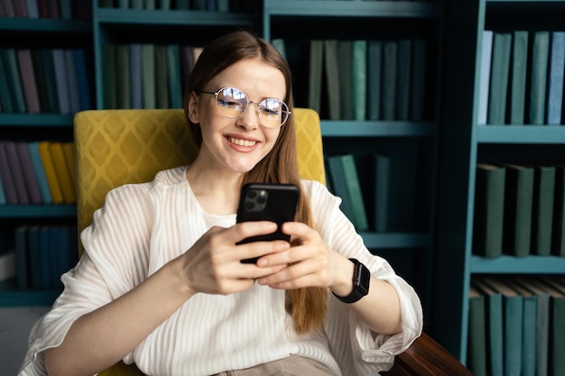 Scrive un messaggio in una chat una donna con gli occhiali lavora usa un telefono in un ufficio in uno spazio di coworking