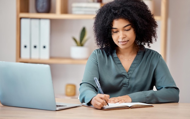 Scrivere taccuino e laptop con una donna d'affari al lavoro secondo il suo programma alla sua scrivania in ufficio Penna del computer e pianificazione con una designer donna o dipendente che lavora alla pianificazione nella sua startup