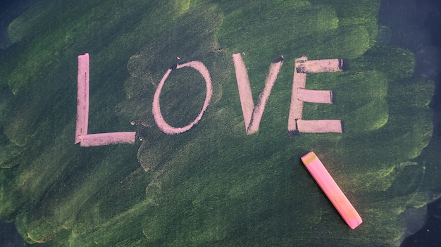Scrivi una parola d&#39;amore con pastelli di gesso su una lavagna di scuola.