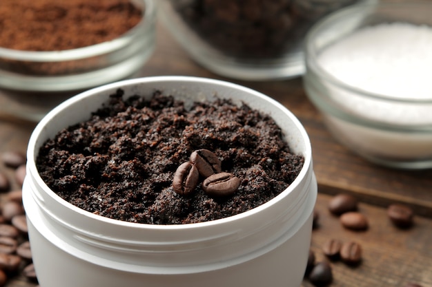 Scrub al caffè fatto in casa in un barattolo bianco per viso e corpo e vari ingredienti per fare lo scrub.