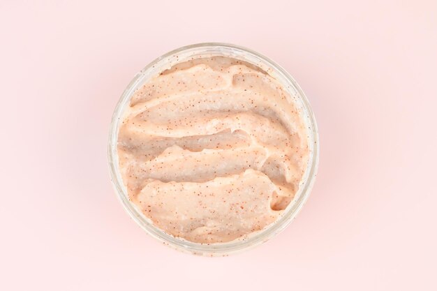 Scrub naturale in contenitore su sfondo rosa pastello Cosmetici fatti in casa per spa