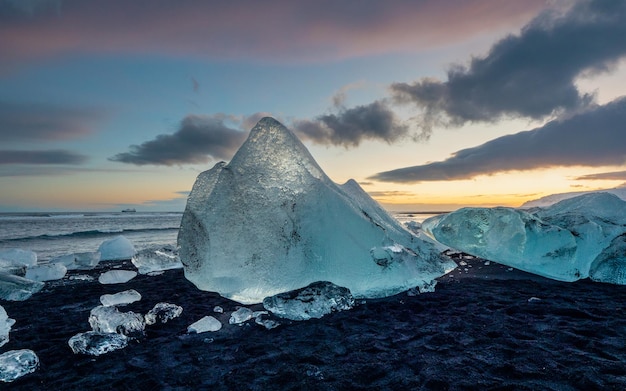 Scultura di ghiaccio che si scioglie sulla spiaggia nera alla luce della sera