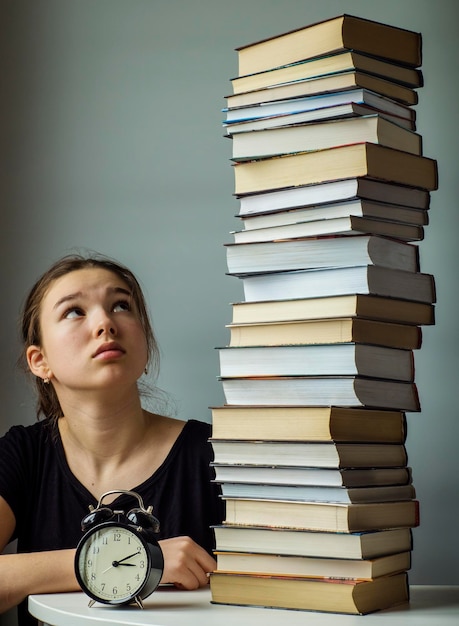 Scuola adolescente scioccata una pila di libri e una sveglia sul tavolo concetto di scadenza