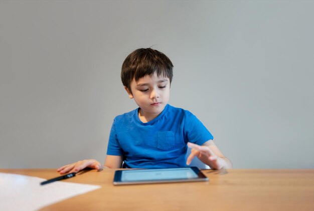 Scuola per bambini che impara in classe online a casa Bambino che usa il tablet per fare i compiti Giovane ragazzo che studia videochiamata online Elearning o concetto di istruzione Homeschooling